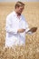 Scientist With Digital Tablet Examining Wheat Crop In Field