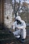 Scientist doing research outdoors, wearing white coverall and gas mask