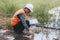 Scientist Ecologist taking a water sample and reading ph value at river. Water pollution and conservation and management of water