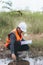 Scientist Ecologist taking a water sample and reading ph value at river. Water pollution and conservation and management of water