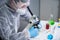 Scientist examining sample with a microscope, doing medical research in science laboratory. Male laboratory assistant in