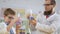 Scientist and his pupil holds in hands flasks with steaming colorful liquids