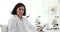 Scientist holds clipboard sitting at table with microscopes