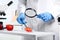 Scientist with magnifying glass exploring slice of tomato in laboratory  closeup. Poison detection