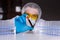 Scientist in mask, cap, goggels and rubber gloves holds blood sample in test tube among racks of vials in laboratory