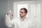 A scientist or a medical worker in a lab coat working in biotechnological laboratory, mixing reagents in a glass flask