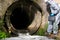 Scientist in protective clothing, with a suitcase enters the drain pipe