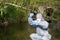 A scientist in a protective suit and mask collects a sample of water in a flask with a blue liquid