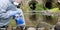 A scientist in a protective suit and mask, collects a sample of water in test tubes, against the background of drain pipes, there