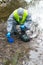 Scientist in a protective suit and mask, conducts rapid analysis of the terrain water and soil