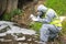 The scientist, in a protective suit, mask and gloves, takes the liquid from the river in test tubes, for a sample