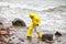 Scientist in protective suit with silver case walking on rocky beach