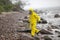 Scientist in protective suit with silver case walking in on rocky beach