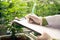 Scientist recording data from gratifying cannabis plant in curative green house.