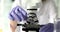 Scientist in rubber gloves adjusts electronic microscope