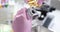 Scientist in rubber pink gloves holds automotive part and pours lubricating oil