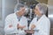 Scientist speaking to colleague holding clipboard in factory