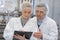 scientist speaking to colleague holding clipboard in factory