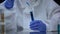Scientist of toxic lab examining sample of blue ionizing radiation liquid danger
