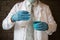 Scientist wear white coat and blue gloves holding glass test tube and laboratory beaker. Chemist examines chemical test tube