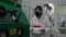 Scientist wearing protective suit and carrying a jar of toxic liquid inside a biohazard area