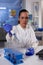 Scientist woman holding micropipette dropping blue solution