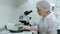 Scientist working with microscope, calculating and taking notes in laboratory