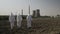 Scientists dressed in hazmat suits carefully walking across a contaminated field near a power plant -