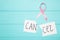 Scissors cutting a piece of paper with Cancer word with pink ribbon. Breast cancer awareness symbol