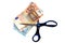 Scissors cutting a wad of euro banknotes on a white background
