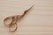Scissors for needlework in the form of a bird of gold color on a wooden background