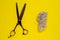 Scissors with shred of pet fur and bunch of wool or fur on bright yellow background. Great copy space for any text or design work