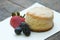 Scones with strawberries, blueberry and mulberry on wooden table