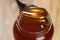 Scooping organic honey with spoon from glass jar