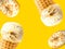 Scoops of delicious salted caramel toffee vanilla ice cream in waffle cones glazed donuts flying on bright yellow background