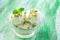 Scoops of lime ice cream with lemon zest, mint, pistachio in a bowl or plate on green