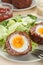 Scotch eggs cut in halves on a plate