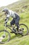 Scotland - August 14, 2010: Cyclists descending down a steep slope among the muddy mountains