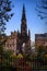 The Scott Monument in Edinburgh Scotland stands tall and dark between some branches