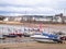 Scottish coastal scene with sailing sloops on beach at low tide.