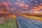 Scottish Country Road in Autumn as the sun goes down leaving a dramamtic blazing red sky. The far distance is Hazy due to the