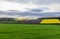 Scottish farmland features yellow rapeseed and freshly ploughed land, beneath a dynamic sky