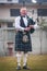 Scottish piper from Scotland in traditional outfit with tartan kilt playing bagpipe