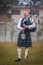 Scottish piper from Scotland in traditional outfit with tartan kilt playing bagpipe