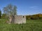 A Scottish stone ruin with an unusual curved end wall in a field with a small stream flowing through it near Guthrie.