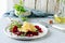 Scramble of eggs with carpaccio of baked beets with walnuts, aromatic herbs and arugula on a plate.