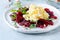 Scramble of eggs with carpaccio of baked beets with walnuts, aromatic herbs and arugula on a plate. Delicious healthy breakfast.