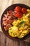 Scrambled eggs with chives, bacon and tomatoes close-up. Vertical top view