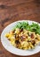 Scrambled eggs with ham, olive and arugula salad in white plate on wooden table