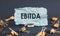 A scrap of blue paper with clips on a gray background with the text - EBITDA Earnings Before Interest, Taxes, Depreciation and